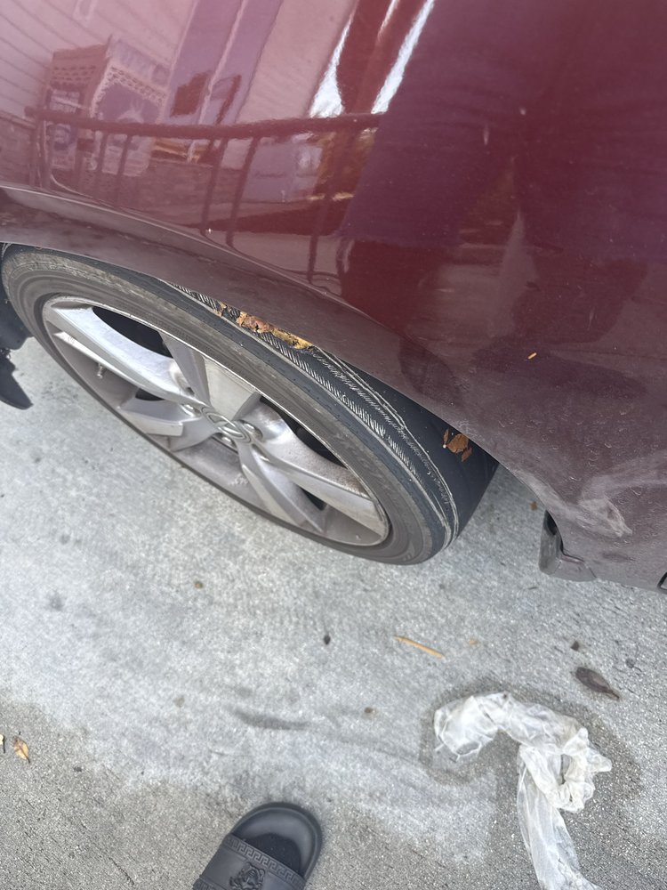 Close-up of a completely flat tire on a red vehicle parked on the street.