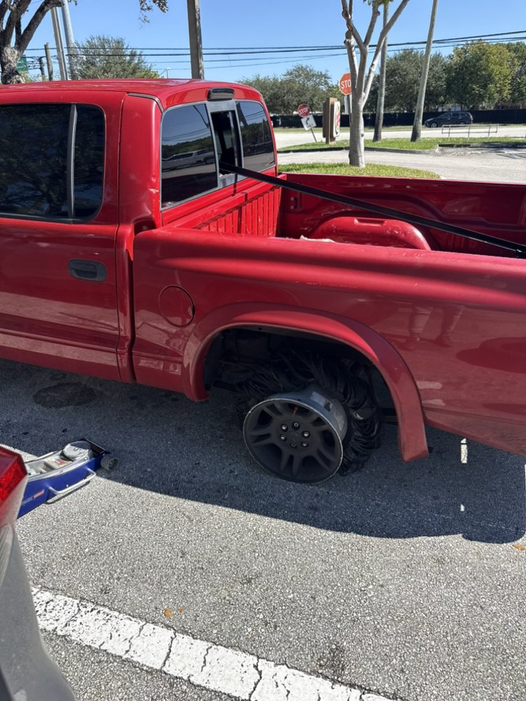 Side profile view of a red pickup truck parked in a parking lot.