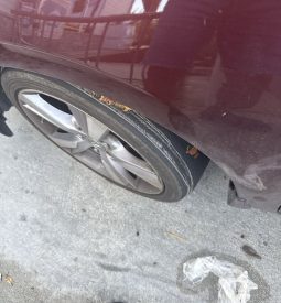 Close-up of a completely flat tire on a red vehicle parked on the street.
